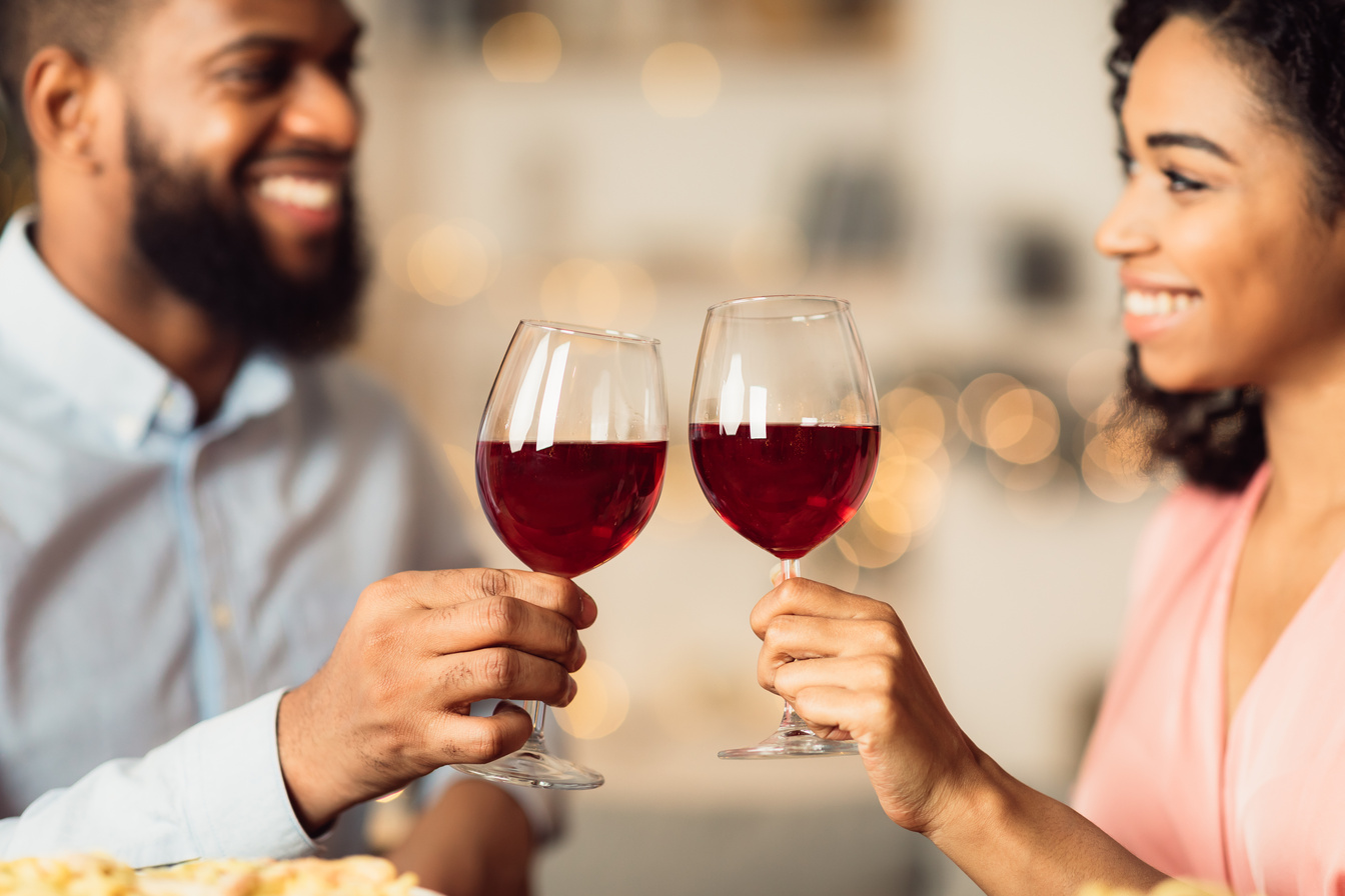 Smiling black woman and man drinking red wine
